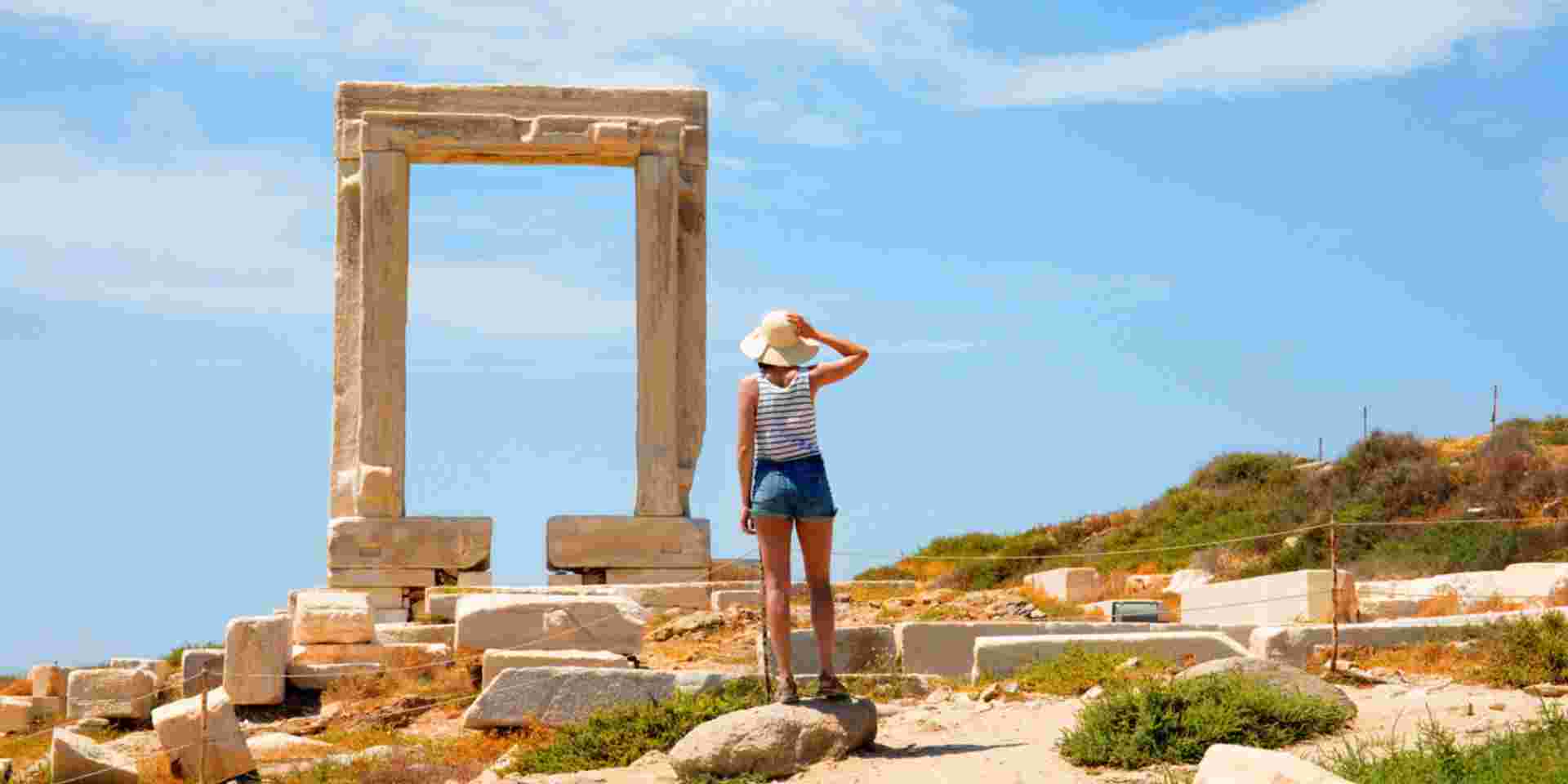 Greece , cyclades islands, Naxos Island. female tourist looking at Temple of Apollo mid day honeymoon in naxos_feature