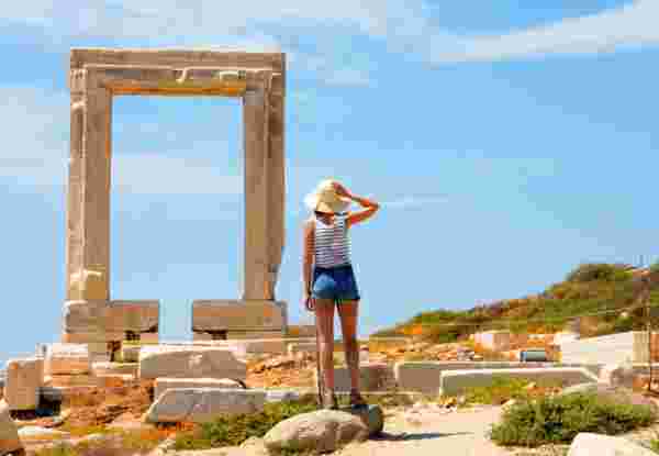 Greece , cyclades islands, Naxos Island. female tourist looking at Temple of Apollo mid day honeymoon in naxos_feature
