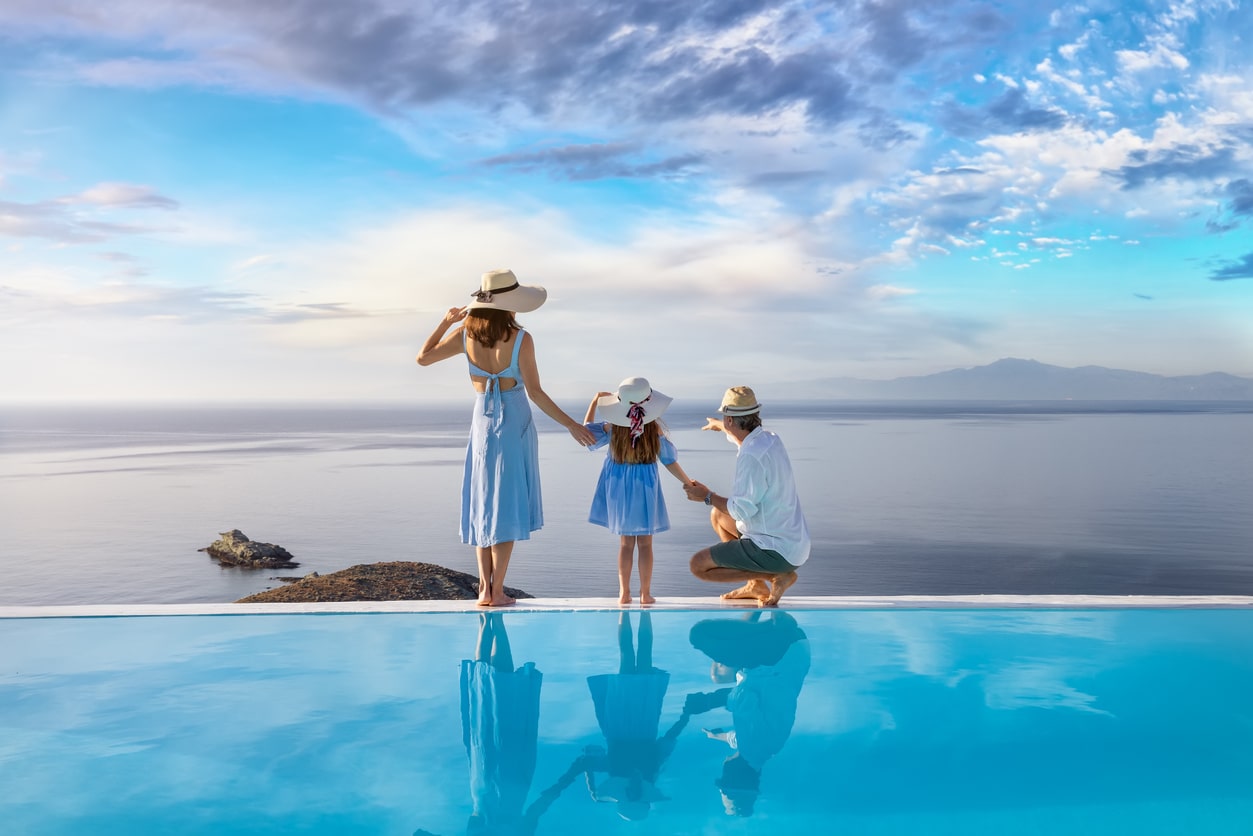 Santorini with kids. Family stands at the edge of a swimming pool