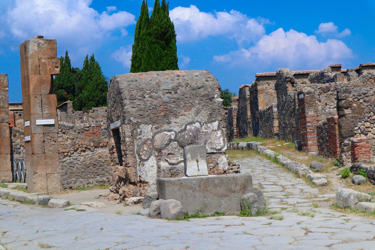 Stone-paved street and ruins in Pompeii, Italy, highlighting ancient Roman architecture and urban design.