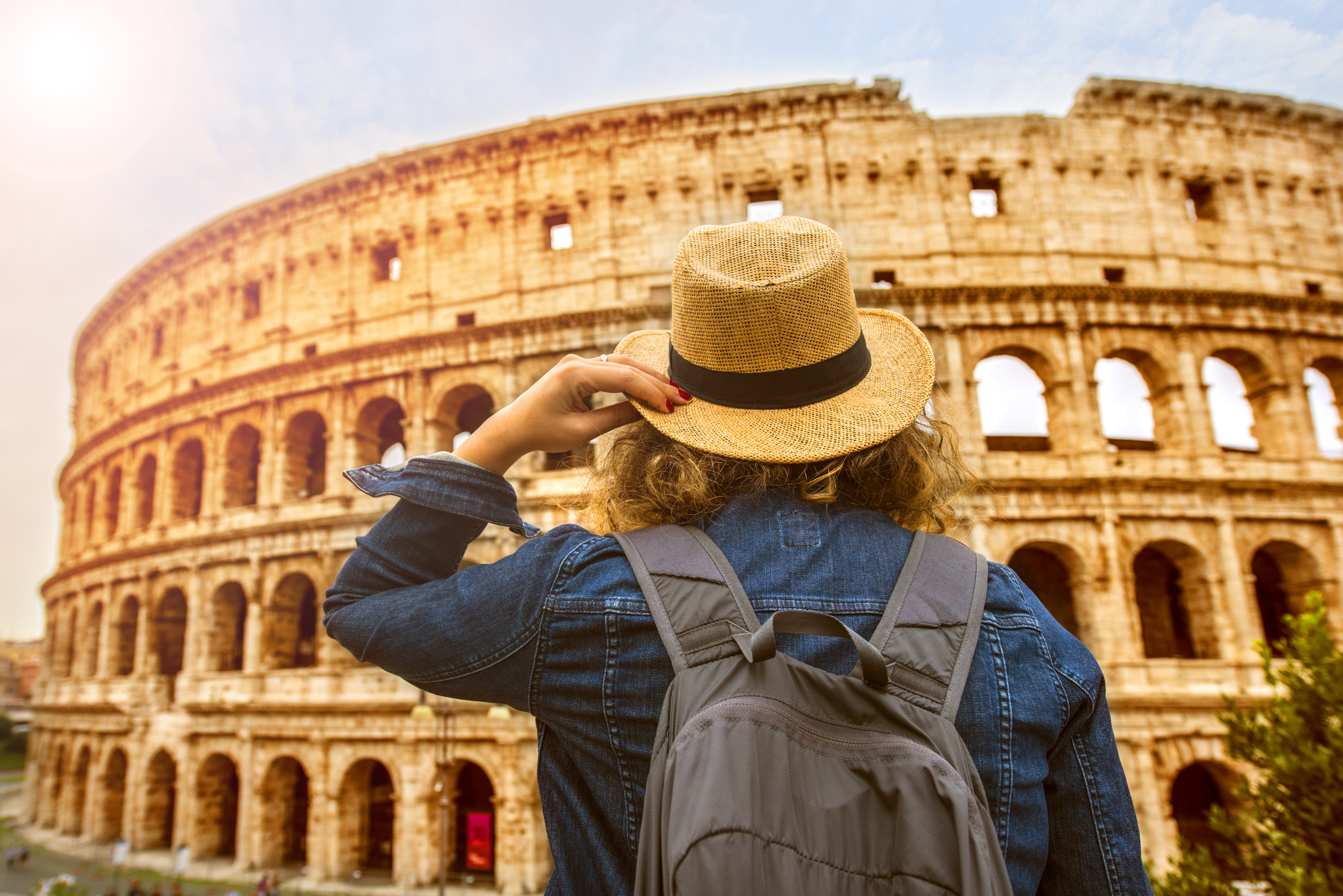 Torist woman with backpack looking at Colosseum Rome, Italy.