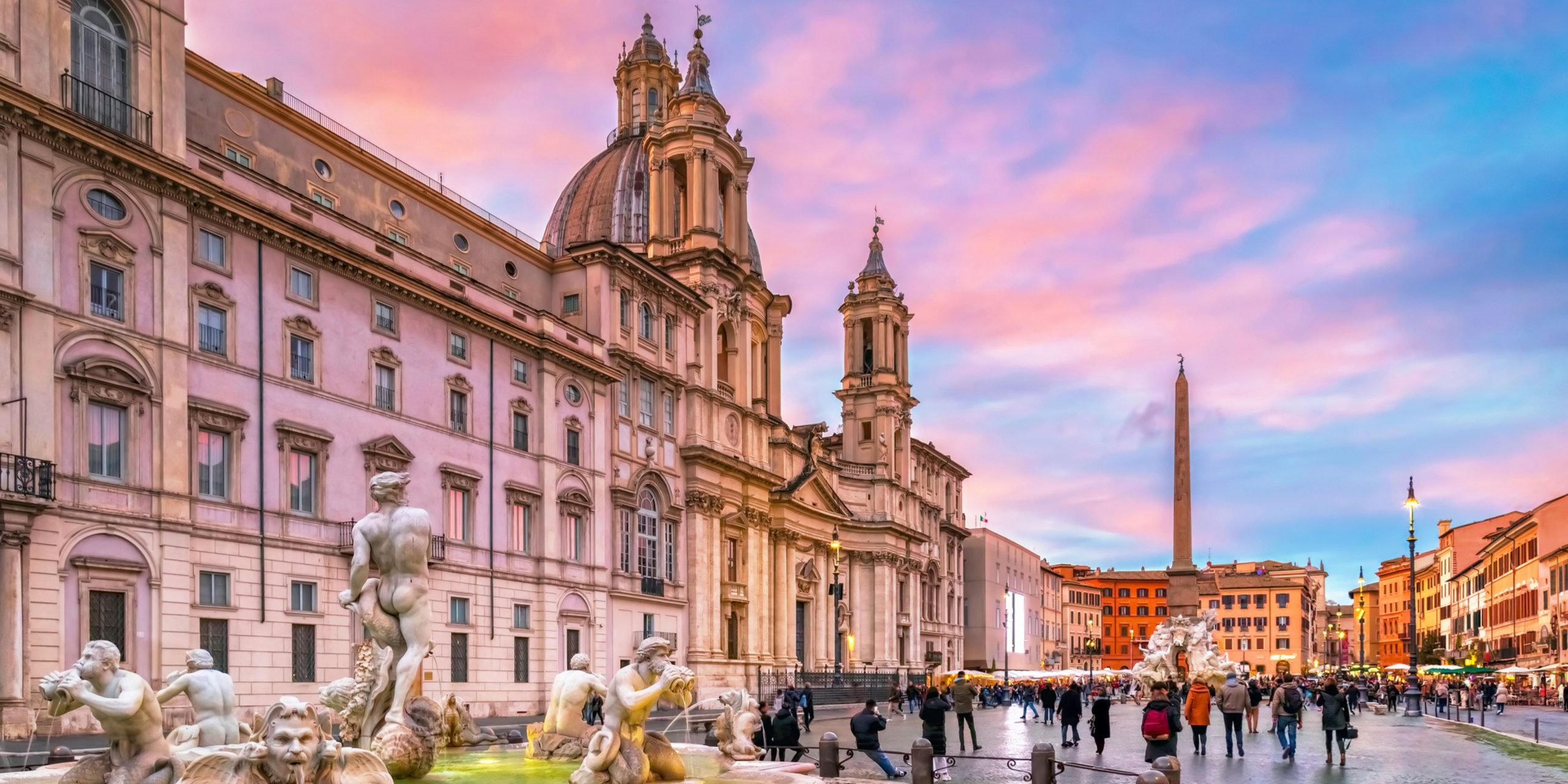 Piazza Navona in Rome Italy, crowded with tourists, on a winter day, just before sunset. In the foreground the famous Fontana del Moro.