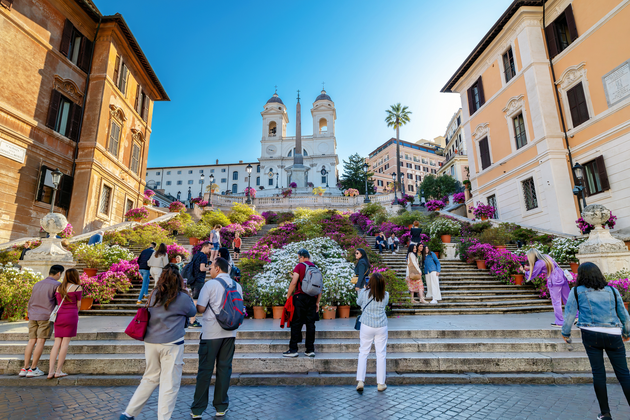Rome, Italy - April 26, 2023: Piazza di Spagna with the beautiful staircase with the colorful flowers in spring. People take selfies with smartphones.