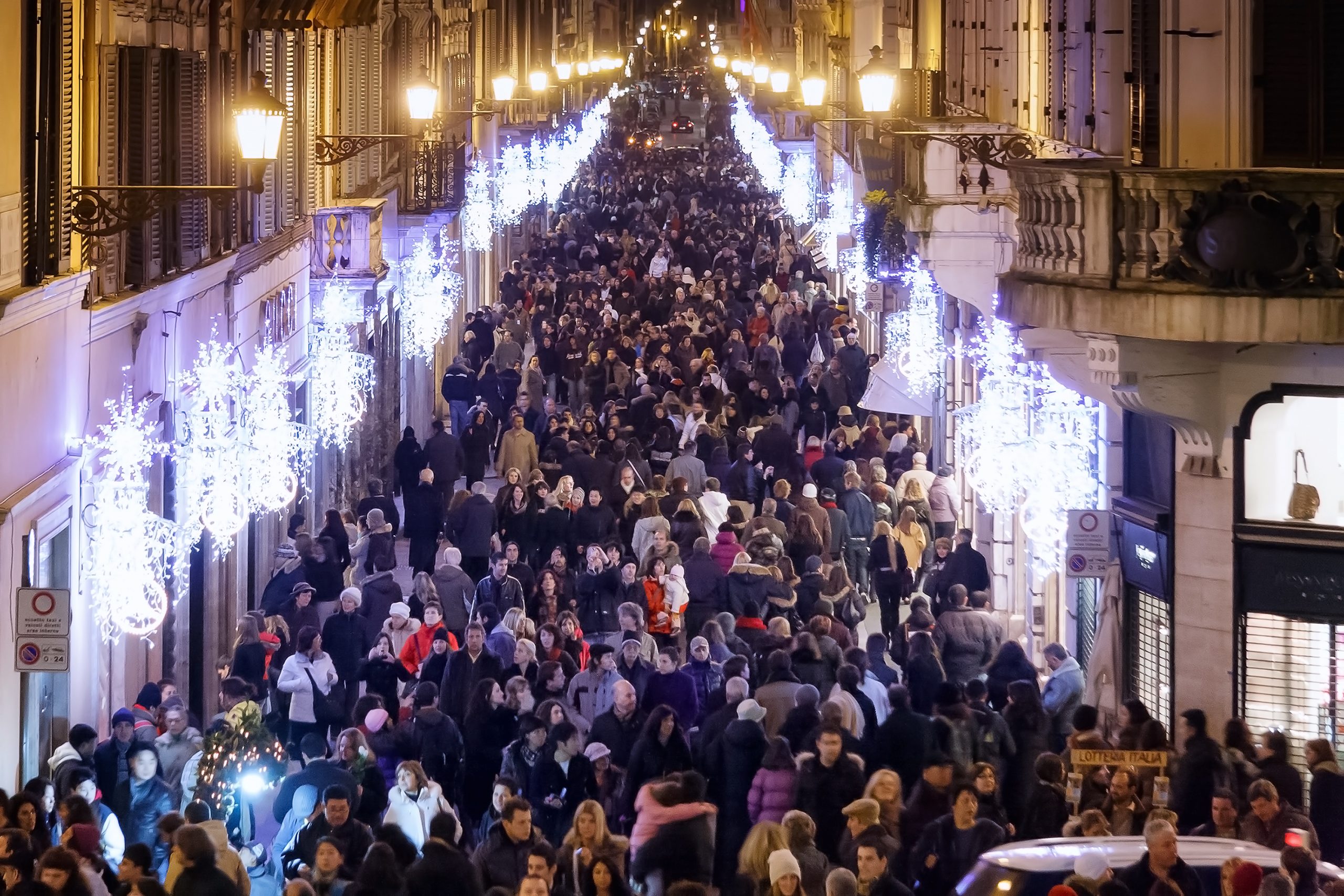 Crowd in Via dei Condotti for Christmas shopping, near the Spanish Steps. The road appears decked out with lights and the Christmas decorations.
