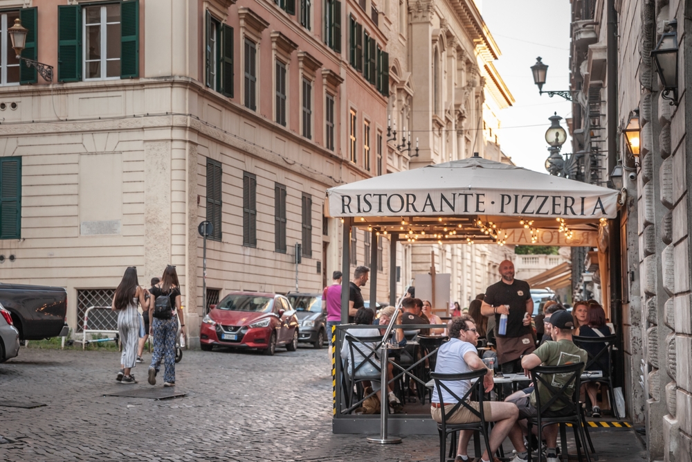 Outdoor restaurant and pizzeria terrace on a cobbled street in Rome’s historic centre