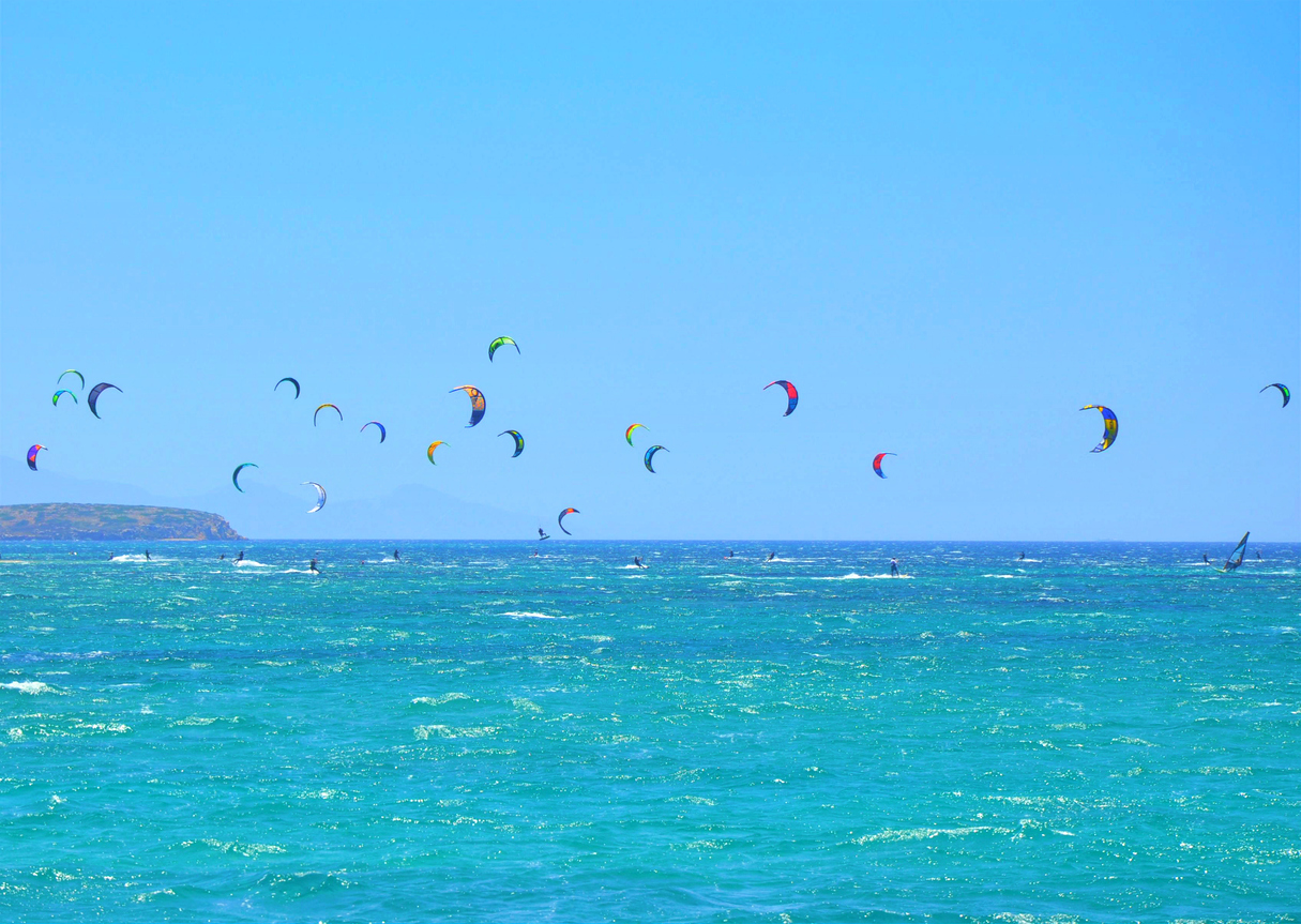Many kiteboarding kite surfers in the distance near on Punda beach on Paros island