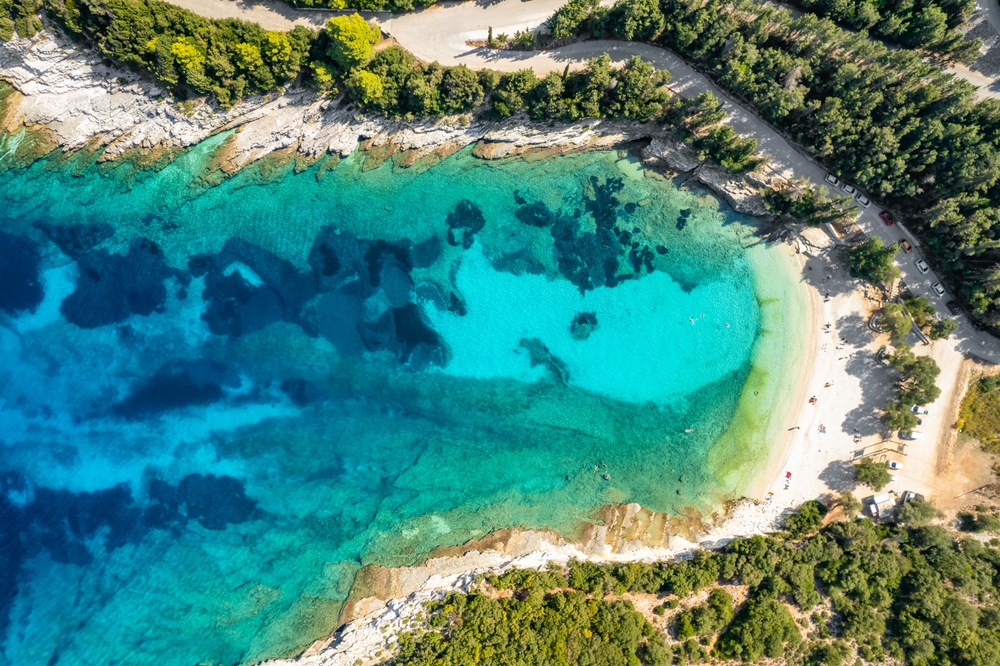 Aerial view of an amazing sea bay with beautiful Emplisi beach near Fiskardo town, Kefalonia island, Ionian sea, Greece. Aerial drone orbit shot. Perfect summer holidays destination
