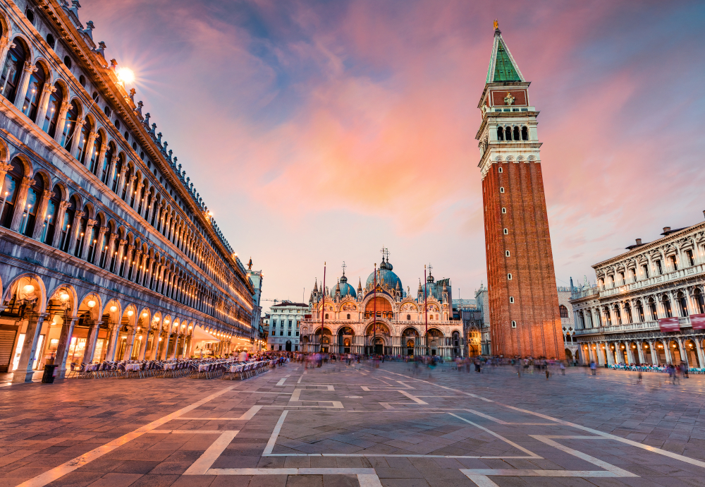 St. Mark’s Square in Venice at sunset with St. Mark’s Basilica and the Campanile illuminated against a pastel sky