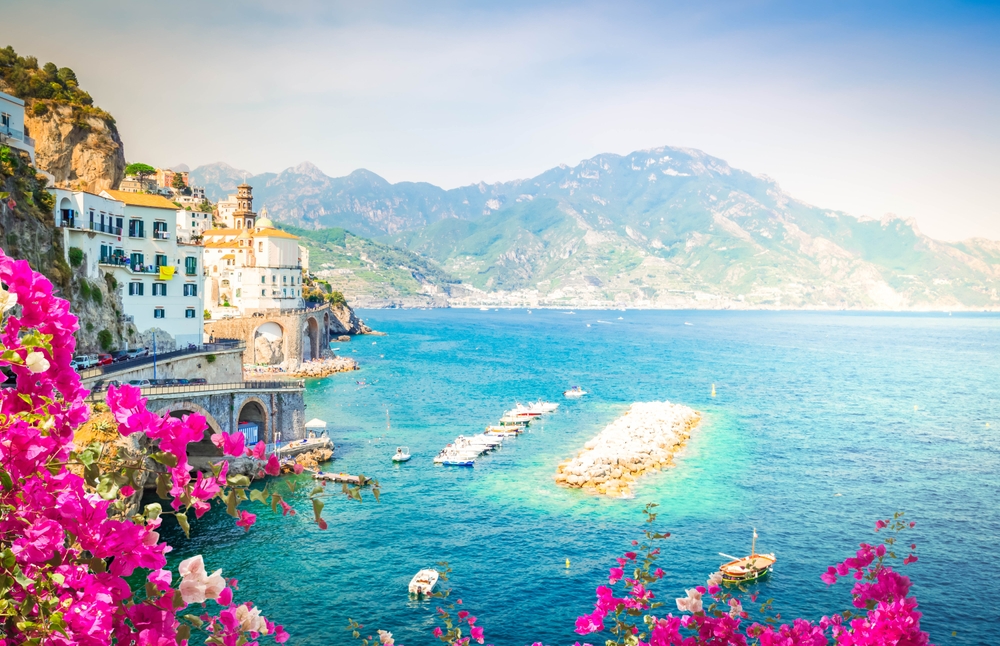 Coastal view of Amalfi on the Amalfi Coast with turquoise waters, cliffs and vibrant bougainvillea flowers