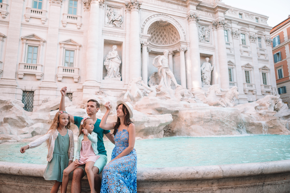 Family with two children visiting the Trevi Fountain in Rome and enjoying a sightseeing stop in the historic city centre 