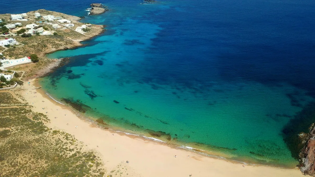 Aerial view of a secluded sandy cove with clear turquoise and deep blue sea