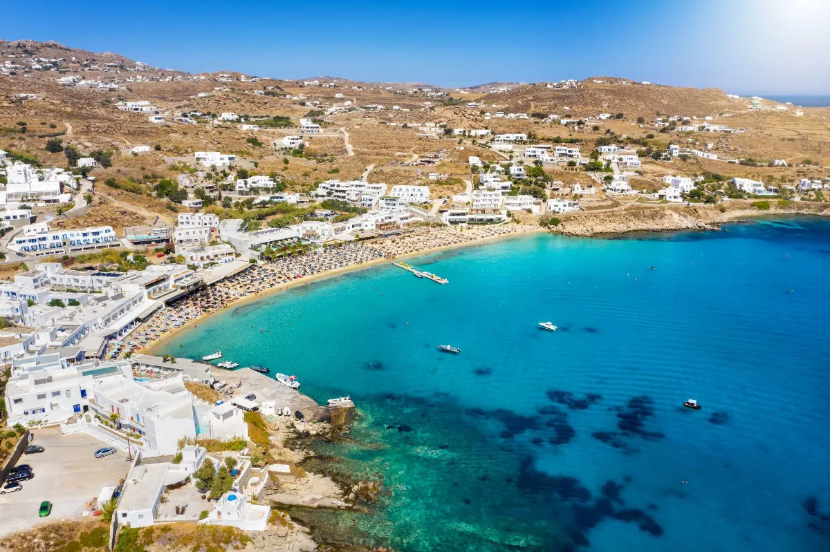 Aerial view of Mykonos coastline with whitewashed buildings and turquoise bay Platis Gialos Beach 1