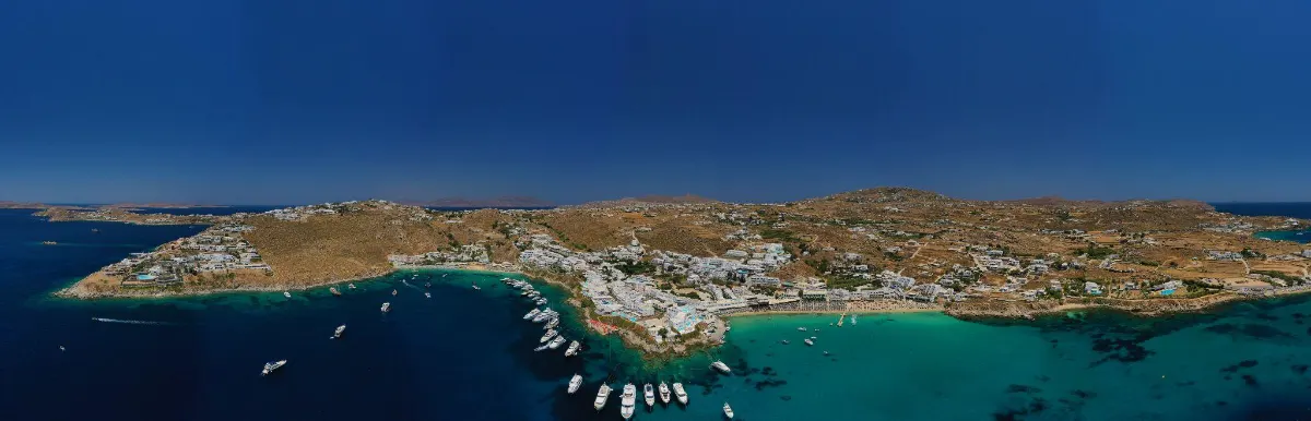 Panoramic aerial view of Mykonos hills, harbor, and yachts along the coast