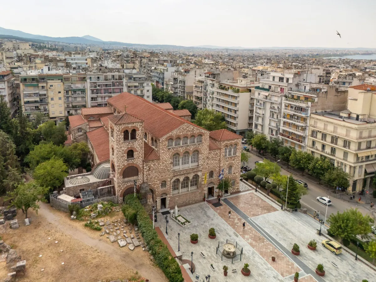 Aerial view of the Byzantine Church of Hagia Sophia in Thessaloniki, its red-tiled roof and stone belfry rising above the surrounding cityscape.
