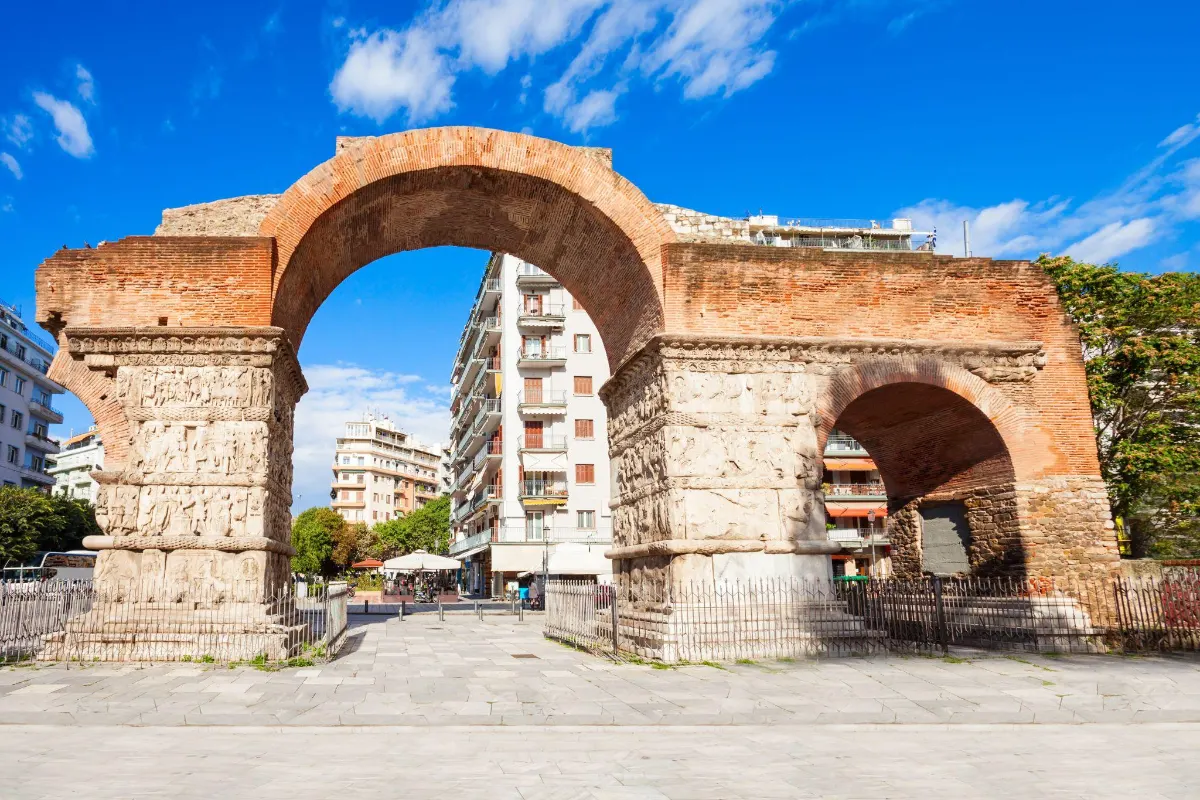 The Arch of Galerius, a weathered Roman brick monument with carved marble reliefs, standing amid Thessaloniki's modern streets.
